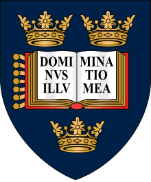 A shield displaying a coat of arms; on a dark blue background, an open book displays the words "Dominus Illuminatio Mea"; two gold crowns above, one below