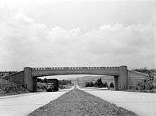 Four-lane highway with overpass, photographed from median