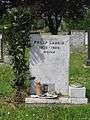 Headstone marking Larkin's grave at Cottingham Cemetery, Cottingham, East Riding of Yorkshire. The headstone is light-grey and has a ground level built-in vase for flowers on its right side. When seen in 2008 there was a small green bush growing just to its left. The headstone is inscribed with the words "Philip Larkin  1922–1985  Writer" on three lines with the dates on the middle line. It is situated in a cemetery with other headstones.