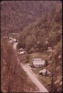 An overhead view of a road through Red Jacket, with houses and trees to either side