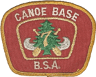 Patch with a red background and a gold border; the text Canoe Base BSA in the border; in the center a silver canoe superimposed with crossed paddles, a green pine tree and the number 7 in gold