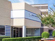 A building with a sign reading "Retro Studios". Trees and a hedge are seen in front of it.