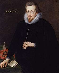 A portrait of Robert Cecil, who is standing at a table wearing black robes.  He has neck length brown hair, and a pointed goatee.  He has gold lettering behind him, which reads "sero, sed serio."