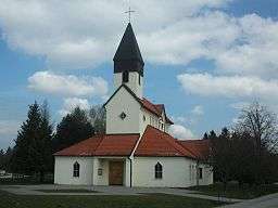 Church with central nave and steeple, white walls and red clay tile roof