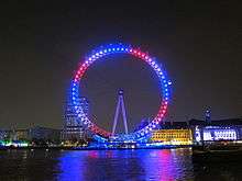 Ferris wheel at night illuminated by blue, red and white