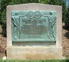 Bronze plaque containing two human figures holding the seal of the United States and the coat of arms of the United Kingdom with a description of the treaty in between them.