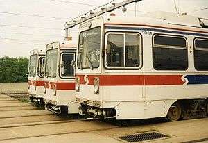 Three abreast white trolleys with a red stripe around the vehicle ends.