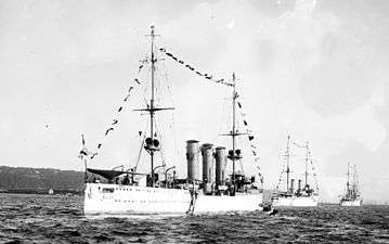 Three large ships painted white in a line close to the waterfront