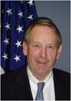 man in business suit, American flag in background