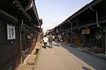 Small street lined by low two-storied wooden houses.