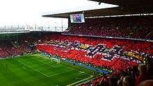 The number "1903" represented in black and red cards held up by fans in a stand at a football stadium.