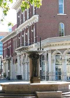 Photograph of the Skidmore Fountain, with the New Market Block in the background showing its cast-iron architecture, in the Skidmore/Old Town Historic District.