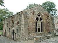 A low stone building with a large window, devoid of glass