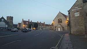 Street scene with houses and pub on the right and trees on the left.