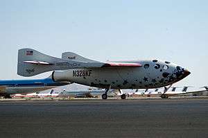 A white rocketship with oddly-shaped wings at rest on a runway.