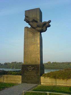 rectangular polished dark stone plinth pointing toward the sky, with a winged plaque and inscription at the base