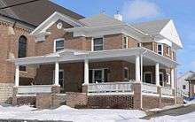 Two-story brick building with wrap-around porch