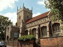 A stone church with a red tiled roof seen from the southeast showing the south aisle, south porch and tower