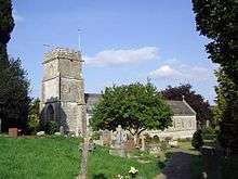 Stone building with square tower, partially obscured by trees.