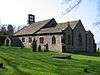 A broad stone church with three gables and a complex bellcote