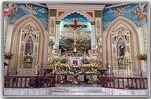 Multicolored church altar with flowers, statues and crucifix