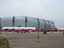 photo of the University of Phoenix Stadium taken from the parking lot, showing the domed stadium against an overcast sky