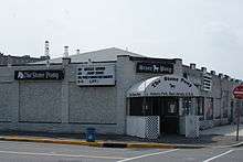 A white brick building on a city street corner. On the side of the building, and on the entrance awning is "The Stone Pony."