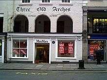 A shop front on the ground floor, above which at the first floor level are three round-headed arches.  Above these is the inscription The Old Arches and the date 1274AD