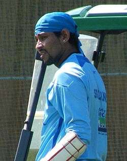 A Sri Lankan cricketer wearing a blue shirt and a blue cloth of his head. He also has a guard on his hand.