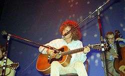 Buckley seated onstage playing guitar