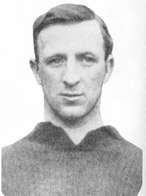 A black-and-white head-and-shoulders photograph of a man wearing a dark shirt. He has short hair.