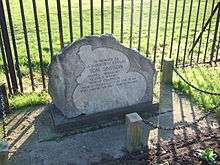 Stone monument in front of a metal fence