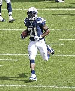 A dark-skinned man holding a football