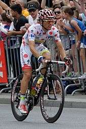 Rafał Majka wearing a white cycling jersey with red polka dots.