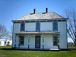 white slatted 2 story house with green door