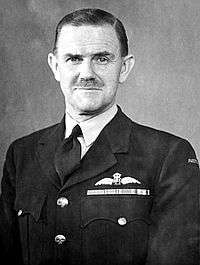 Head-and-shoulders portrait of mustachioed man wearing dark military uniform with pilot's wings above breast pocket