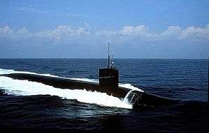 Submarine running on surface in the open seas, creating huge waves in the process.