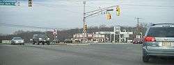 A four-way intersection at a traffic light between a divided highway and a two-lane road. A traffic light resides in the highway median, with a sign blade for U.S. Route 202 and Route 31. Another traffic light arm is to the left with a sign blade reading Old York Road Route 179. A Hess gas station is in the background