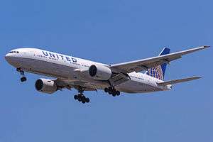 Aircraft landing approach. Front quarter view of twin-engine jet in flight with flaps and landing gear extended.