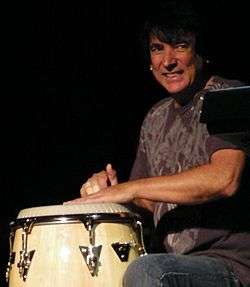 Photo of Walfredo Reyes Jr. playing a conga drum, at a live Chicago concert