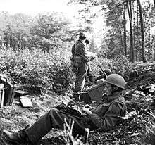 Two men in woods one with a type writer