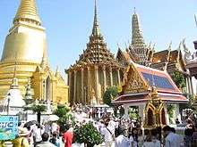 A Thai temple complex with several ornate buildings and a stupa, and a lot of visitors