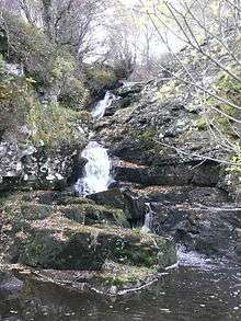 White water down hillside framed with jagged mossy rocks in wood