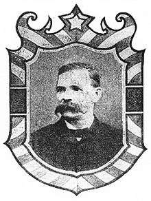 Framed portrait of a white man with an extremely bushy mustache, wearing a dark suit coat and bow tie.