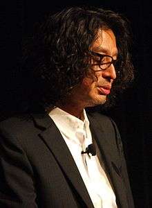 A photograph of a middle-aged Japanese man who is giving a lecture.