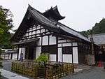 A wooden building with white walls and large gabled roof.